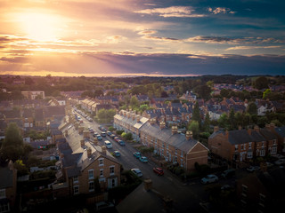 Sun setting with atmospheric effect over traditional British houses and tree lined streets. Dramatic, warm lighting creates a homely mood