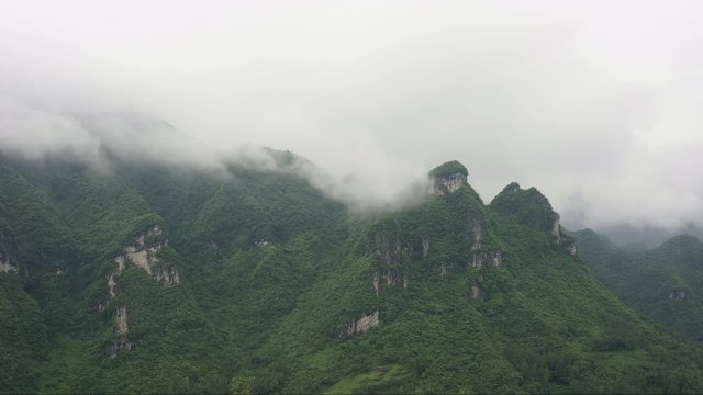 Timelapse of misty clouds on tree covered mountains. Time-lapse of rainy weather caused low clouds and fog over hilly terrain. Epic low hanging clouds cause inclement weather in Chinese mountains.