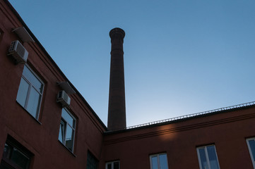 A fragment of an old brick factory building with a pipe.