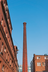 Fototapeta na wymiar urban view - factory pipe and old brick buildings against the blue sky