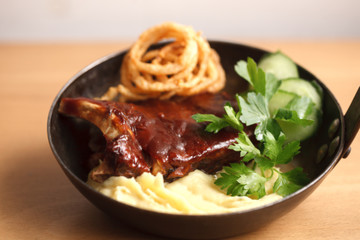 baked barbecue ribs with mashed potatoes in a cast iron pan