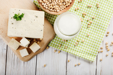 Fototapeta na wymiar Flat lay at Non-dairy alternatives Soy milk or yogurt in mason jar and tofu on white wooden table with soybeans in bowl aside