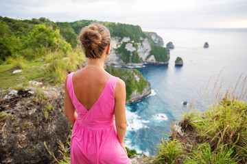  woman sitting on the edge of a cliff and looking at sunset, Nusa Penida