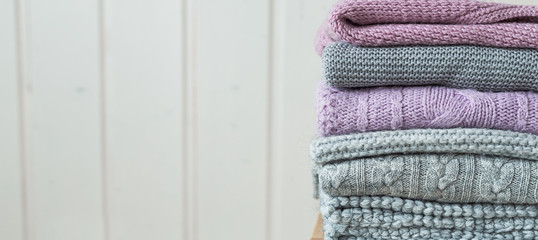 Stack of cozy knitted sweaters on a wooden ladder. Scandinavian style.