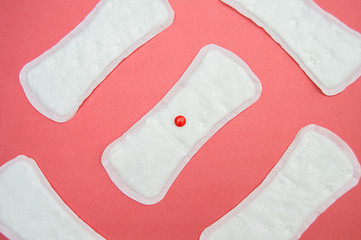 women's sanitary pads and red drops on pink background