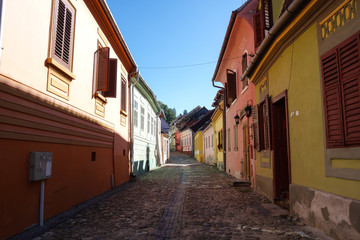 Fototapeta na wymiar Colorful buildings in a narrow alley in Sighisoara (Sighișoara), Romania