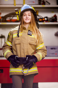 Image of woman firefighter in helmet standing near fire truck