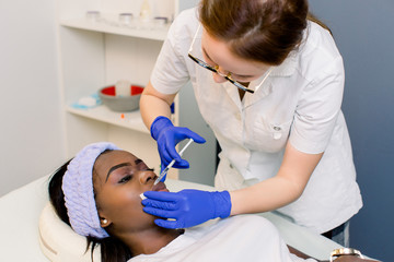 The doctor cosmetologist makes Lip augmentation procedure of a beautiful woman in a beauty salon....