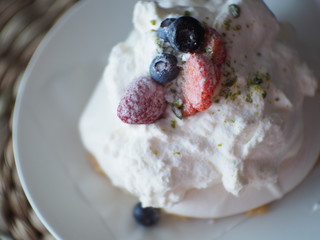 blurred Pavlova cakes with cream and fresh summer berries, soft mist