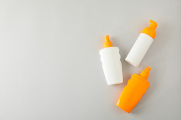 Flat lay composition with sunscreen sprays on grey background. Space for text, top view