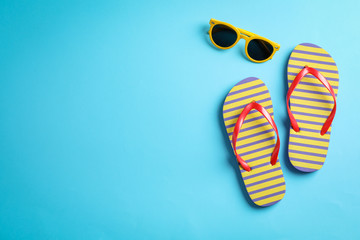Sunglasses and flip flops on color background, space for text © Atlas