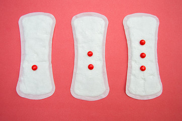 women's sanitary pads and red drops on pink background