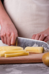 Obraz na płótnie Canvas young woman in an apron cuts potatoes