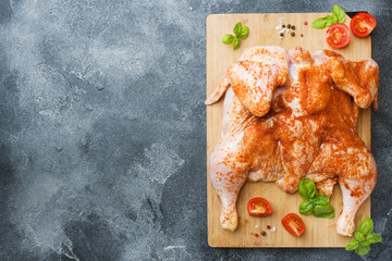 Raw chicken tobacco on a wooden Board with spices and vegetables Copy space