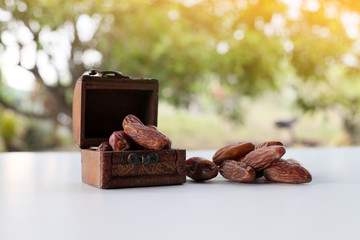Ramadan concept. dry dates in classic wooden box on white wooden table. fresh green background.