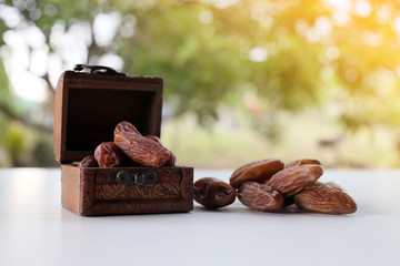 Ramadan concept. dry dates in classic wooden box on white wooden table. fresh green background.