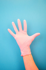 Pointing a finger at number five, wearing pink medical gloves, against a blue background. Good habits, vaccination, medical store, pharmacy.