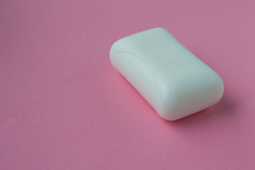 A bar of white soap on a pink background.