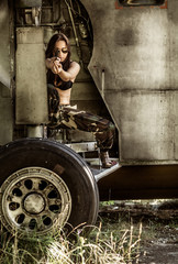 Obraz na płótnie Canvas Portrait of a young girl with mimetic military dress near the old abandoned broken plane. Concept military strong woman.