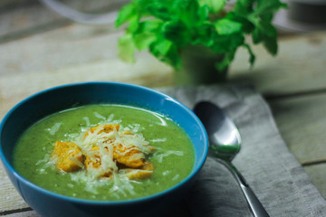 fresh mashed soup with broccoli and green beans in a blue plate on a wooden background