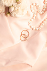 Wedding rings on a pink silk background