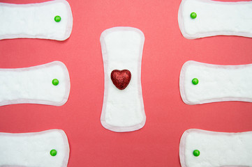 women's sanitary pads and red heart on pink background