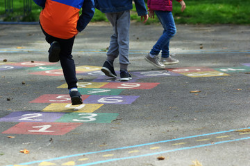 Closeup of kids feet jumping and playing hopscotch in school yard