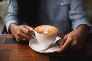 coffee latte art in cafe with woman hand