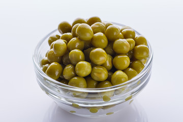canned green peas in a glass bowl on a white background