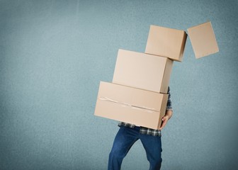 Delivery man carrying stacked boxes in front of face against  background