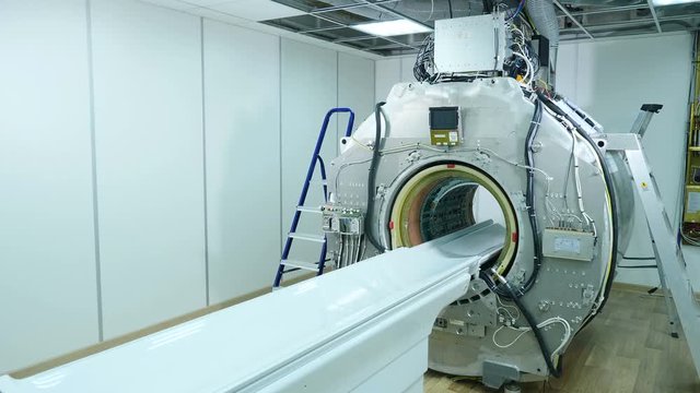 MRI scanner without upper plastic covering panels. MRI machine assembling and installation. Building of new modern hospital with MR-imaging unit in room. Long shot. 4k