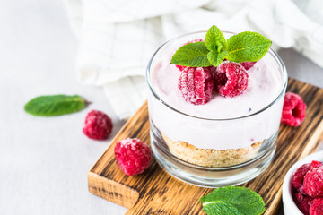 No baked cheesecake with raspberry in glass jar.