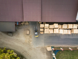 Aerial view of sawmill site during nice spring sunset, wooden pallets stacked next to warehouse