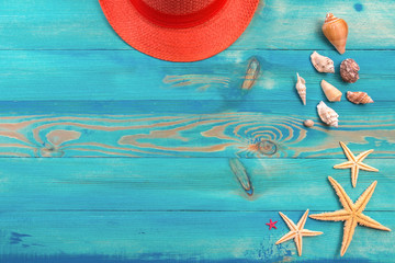 Top view on living coral color hat, seashells and starfish on blue painted vintage wooden texture. Flat lay, copy space.