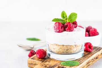 No baked cheesecake with raspberry in glass jar.