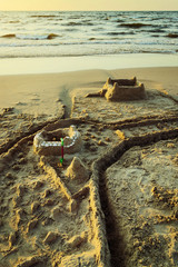 Sandcastle with moat on the Baltic beach at dusk. Summer vacation, leisure activity. Pomerania, Poland.