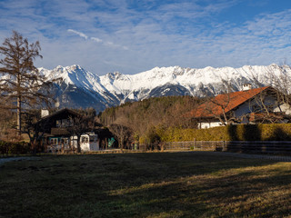 Paisaje Austriaco con campo, casas y al fondo monta&ntilde;as nevadas por la zona de Igls en Innsbruck, invierno de 2018