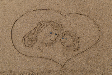 drawing a picture with stones of happy mother's day on sand on the beach.