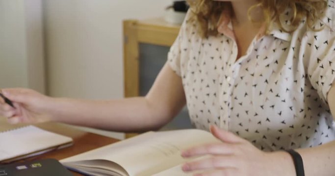 Young studen, blonde woman studying and working behind laptop, with books and notepad