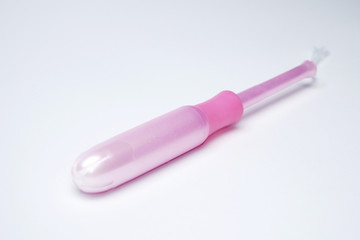 Pink protect, hygienic tampon in applicator close up on white background.