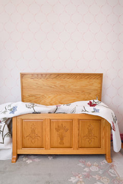 Open Hand Carved Oak Cedar Chest With Blanket In Bedroom With Pink Wallpaper