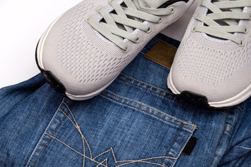 Gray sneakers and jeans. Clothing for walking. Clothing for travel. Sport shoes and blue jeans. Men's shoes on a white background