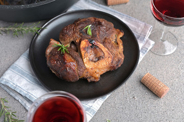 A large piece of fried meat on the bone in a plate and a glass of red wine. Served table for high-calorie lunch.