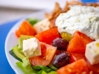 Close up of tomatoes, olives, feta cheese and slices of cucumbers from a famous Greek salad, against a blurred background