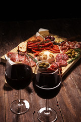 Cutting board with prosciutto, salami, cheese,bread and olives on dark wooden background