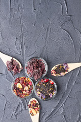 Hibiscus tea, green tea and fruity tea. Set of different herbal and fruit dry teas on stone concrete background. Top view with copy space.