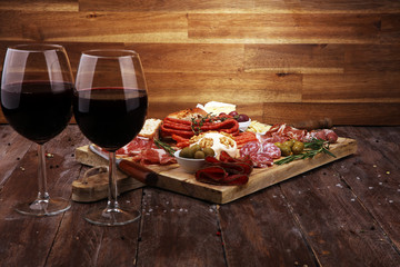 Cutting board with prosciutto, salami, cheese,bread and olives on dark wooden background