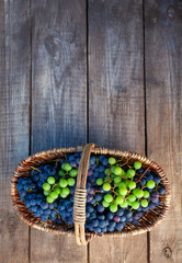 basket with grapes on wooden surface
