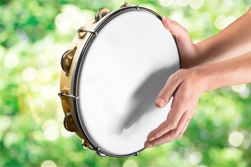 Female hands Playing the tambourine on background
