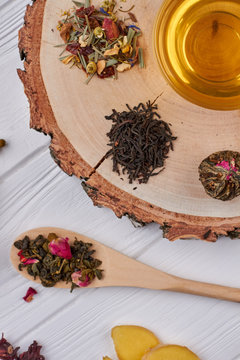 Assorted tea leaves and hot beverage in cup. Composition with different types of dry tea leaves.